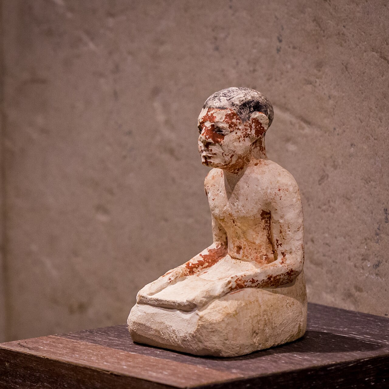 Portrait statuette of an Egyptian scribe sitting on the floor